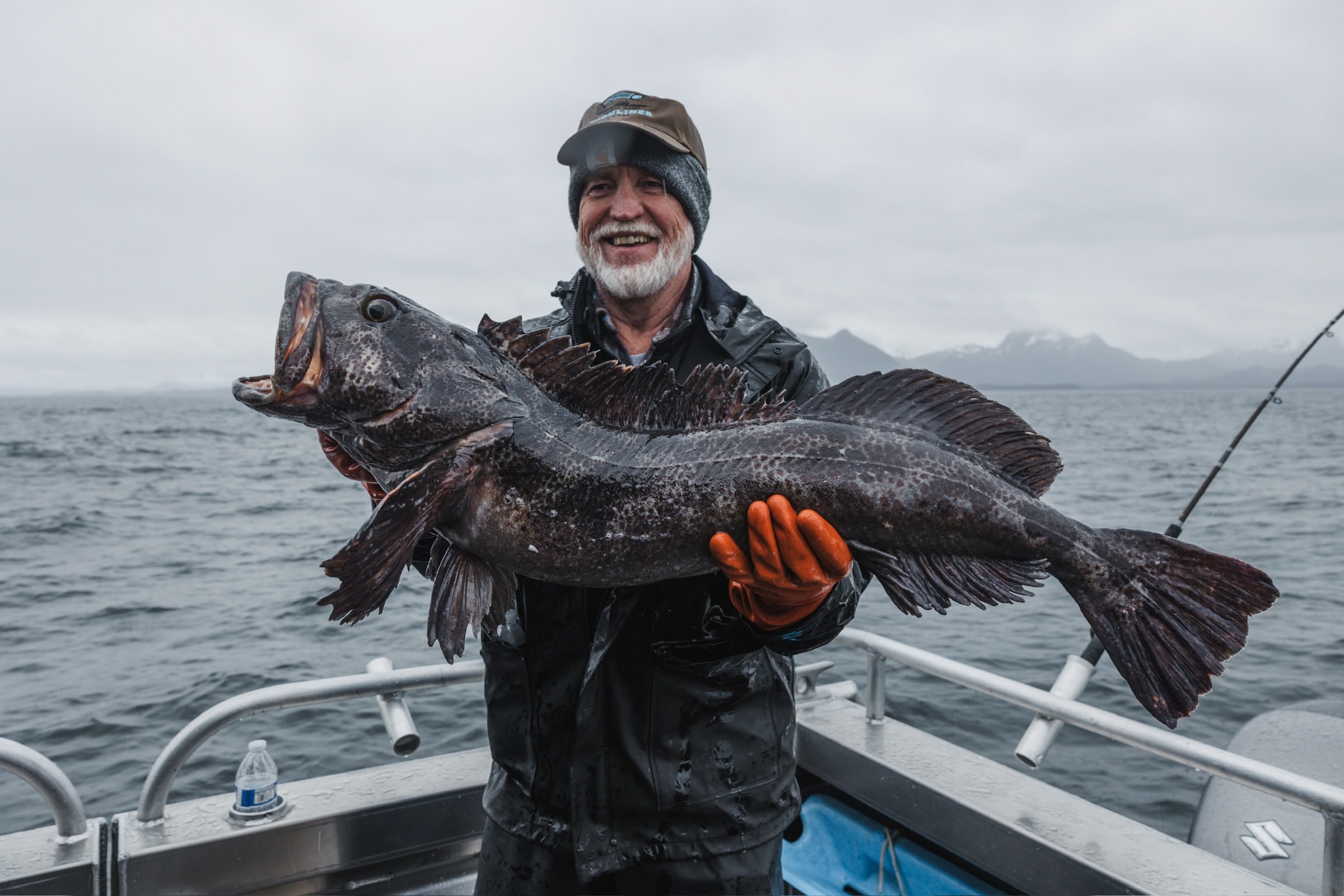 Angler holding a large lingcod caught in Alaskan waters